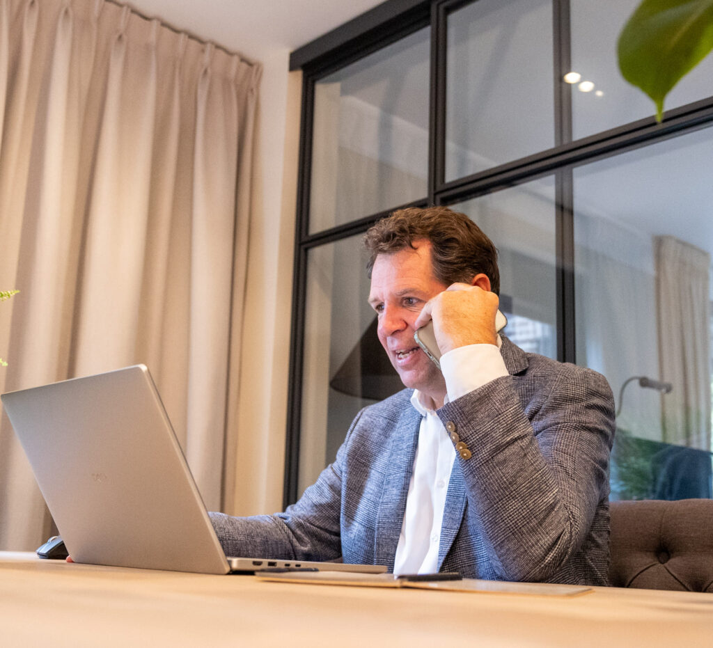 Eigenaar Arjan de Rooy zit achter zijn bureau en voert een telefoongesprek.