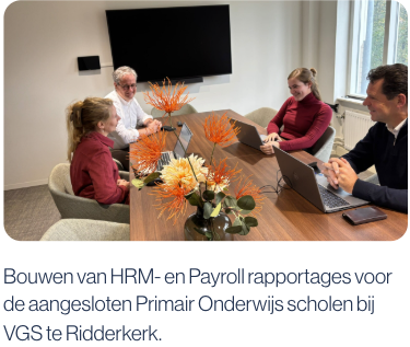 Arjan de Rooy en drie collega's zitten geconcentreerd en betrokken aan een vergadertafel bij VGS, laptops voor zich en omringd door kantoorinrichting.